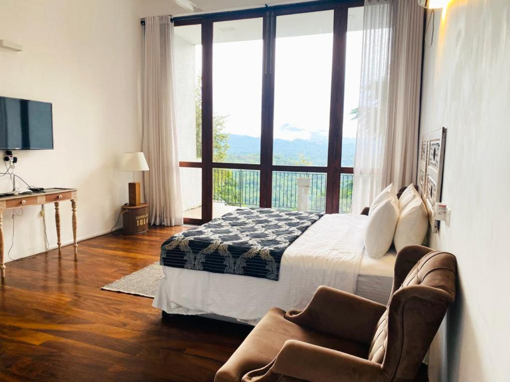 A room at Kandy Casa with floor-to-ceiling windows onto the balcony and the mountains