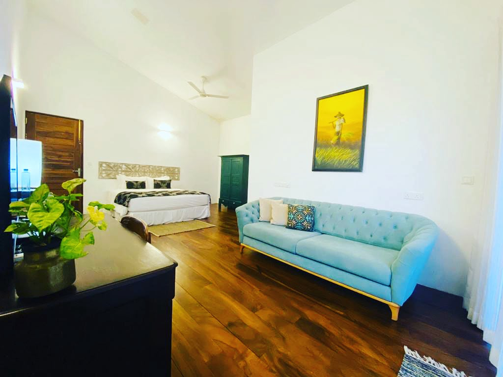 A Superior Double Room at Kandy Casa with its sofa, bed and a painting on the wall