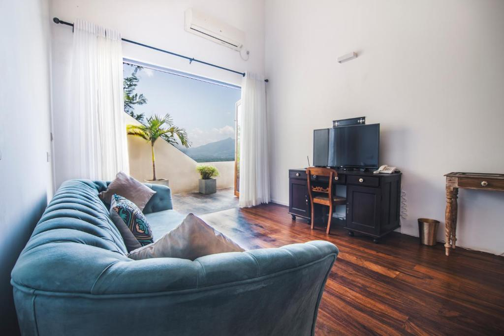 The sofa, desk and TV in a Superior Double Room, with the mountains through the balcony doors