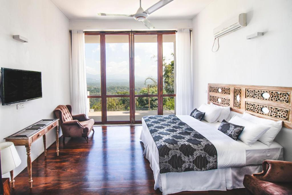The bed in the Superior King Room facing glass doors onto the balcony and the hills