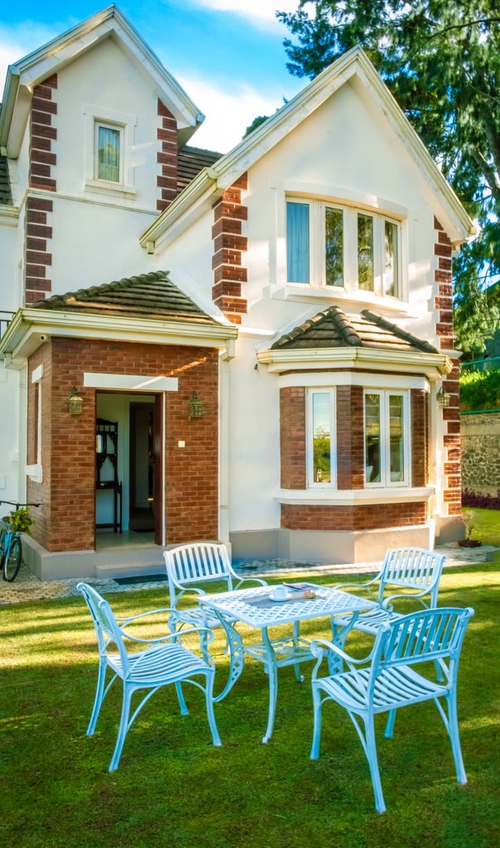 A garden table and chairs on the lawn in front of a cottage at Little England