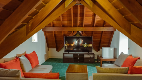 Sofas facing a large TV in the timber-roofed lobby at Little England