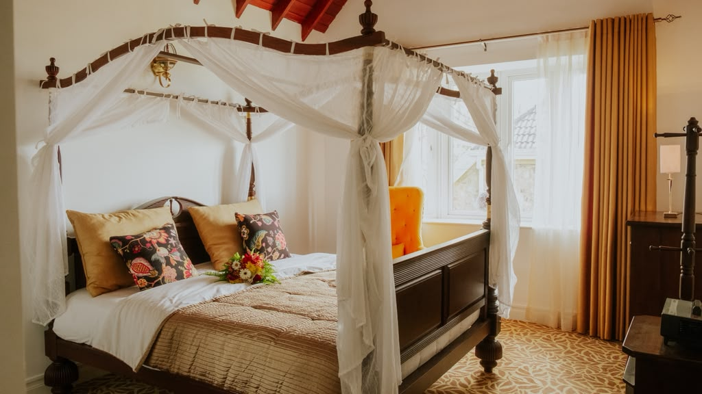 A four-poster bed with white drapes in a room at Little England