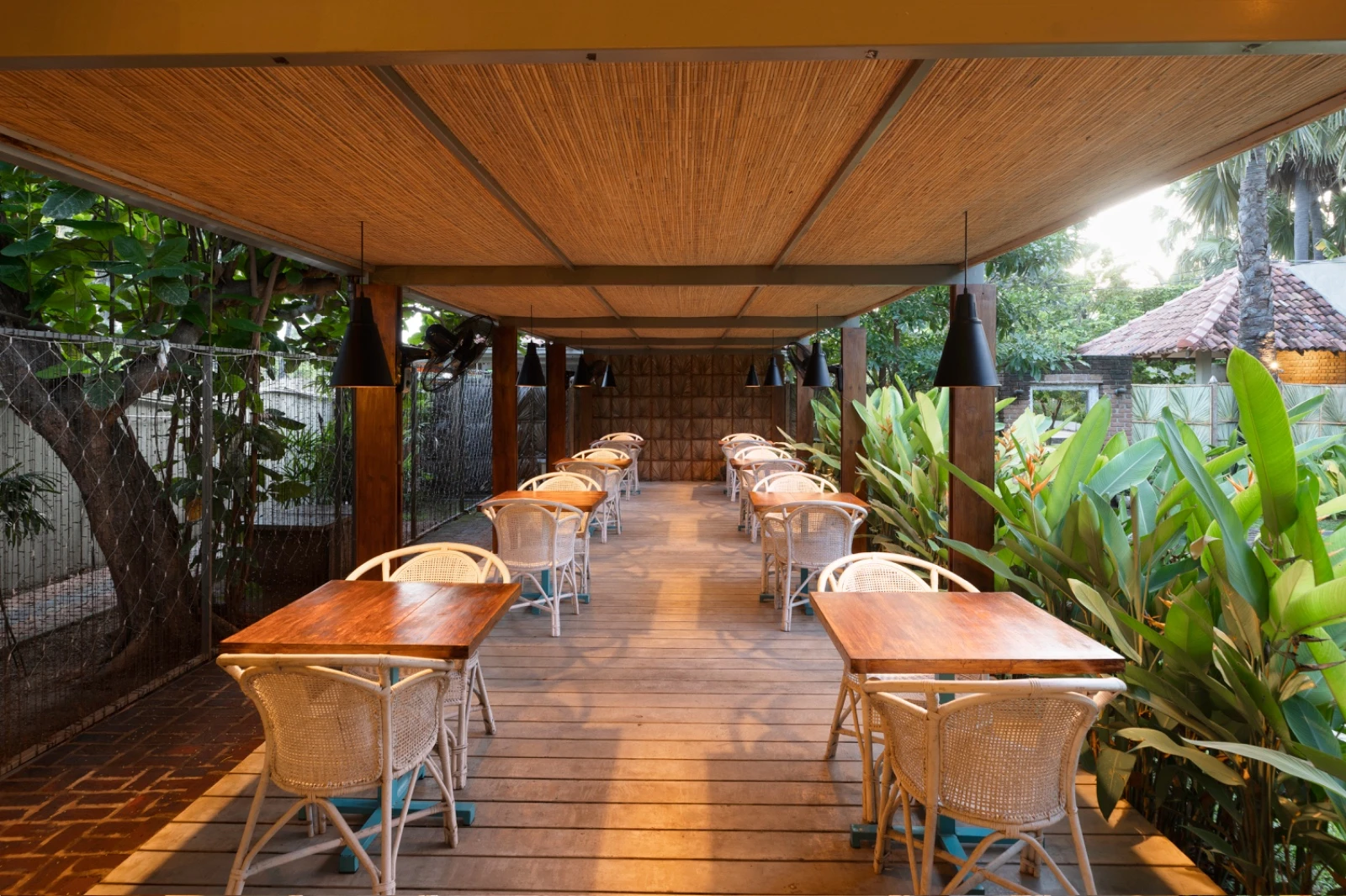The covered dining terrace at Palmera Eco Resort, set with tables among tropical plants