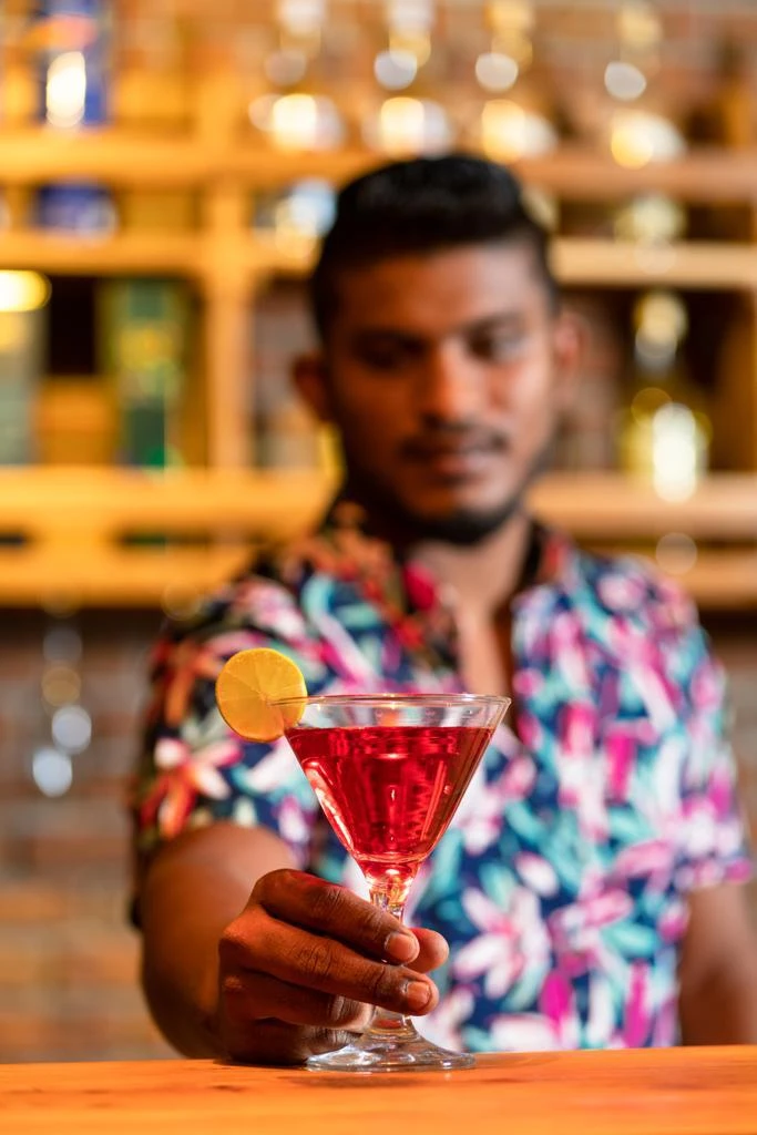 A bartender serving a cocktail garnished with lime