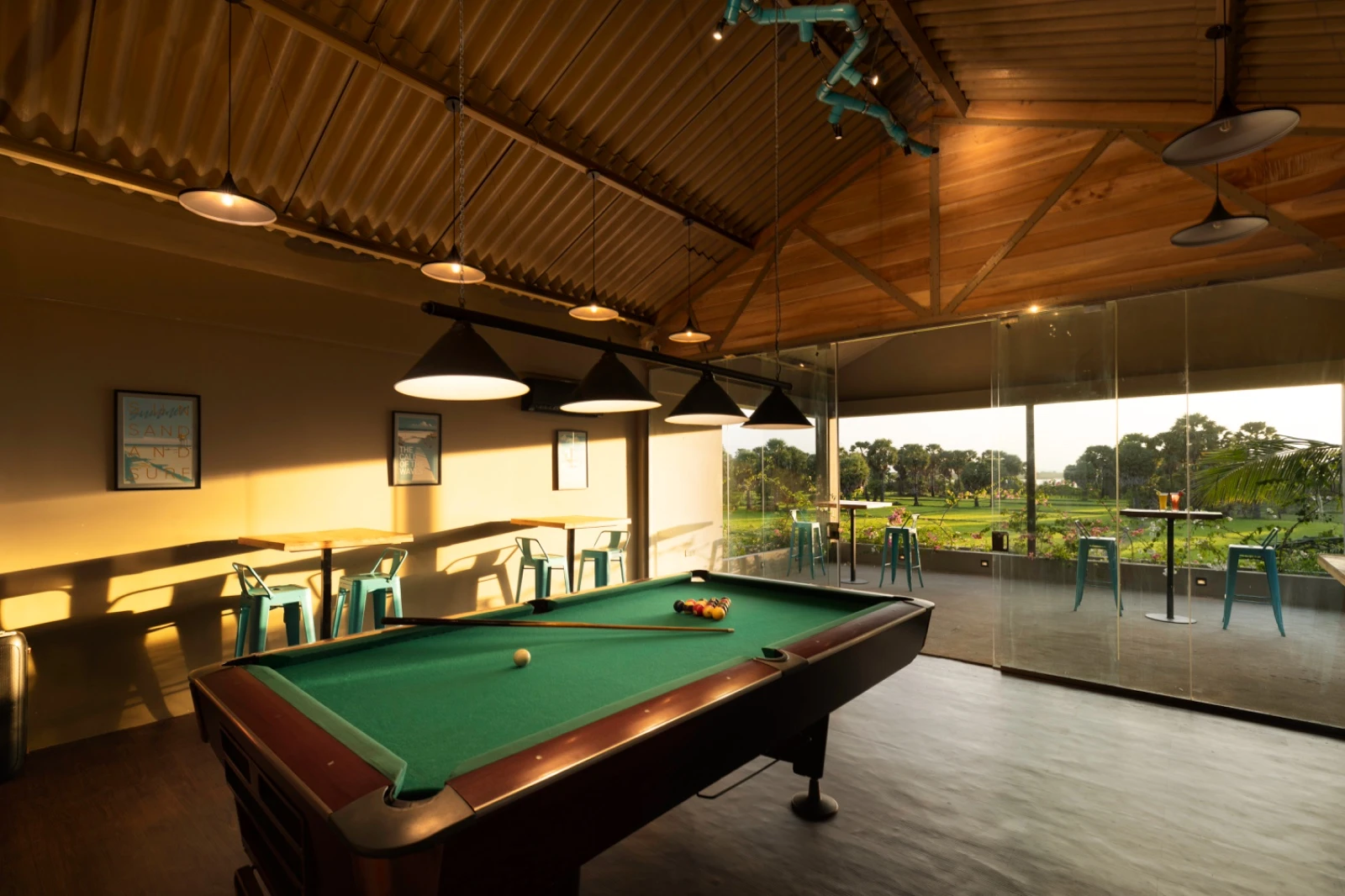 The games room pool table in evening light, with the fields beyond the glass