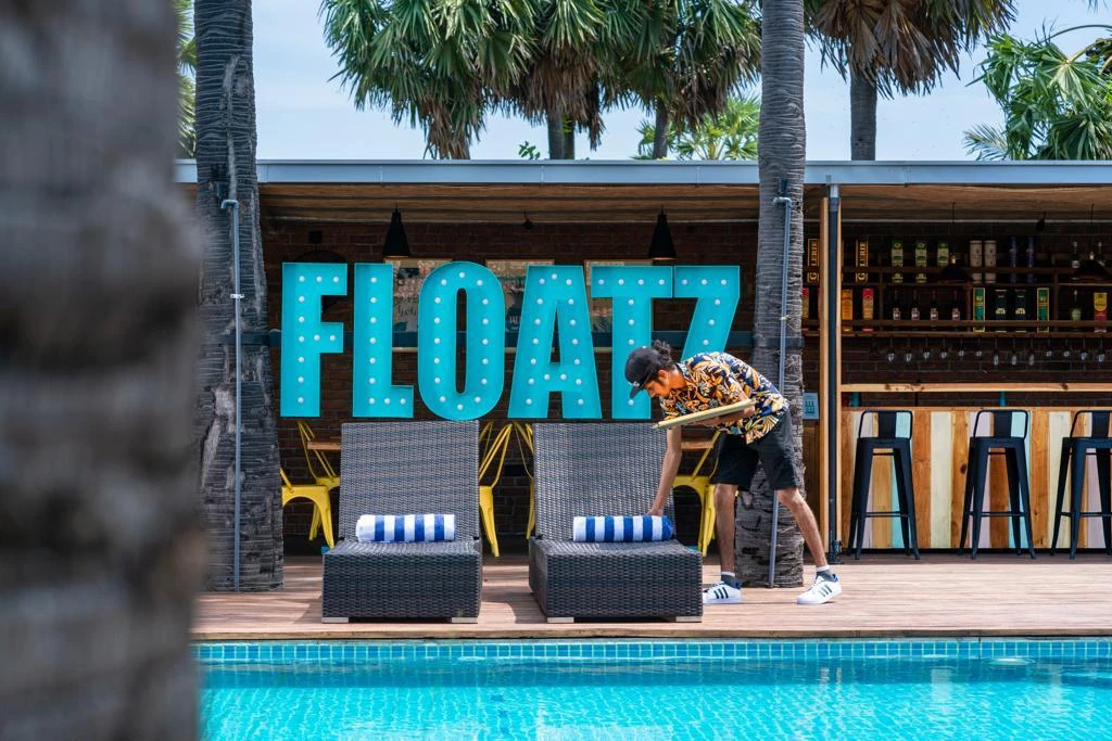 A staff member laying out the poolside loungers in front of the Floatz bar