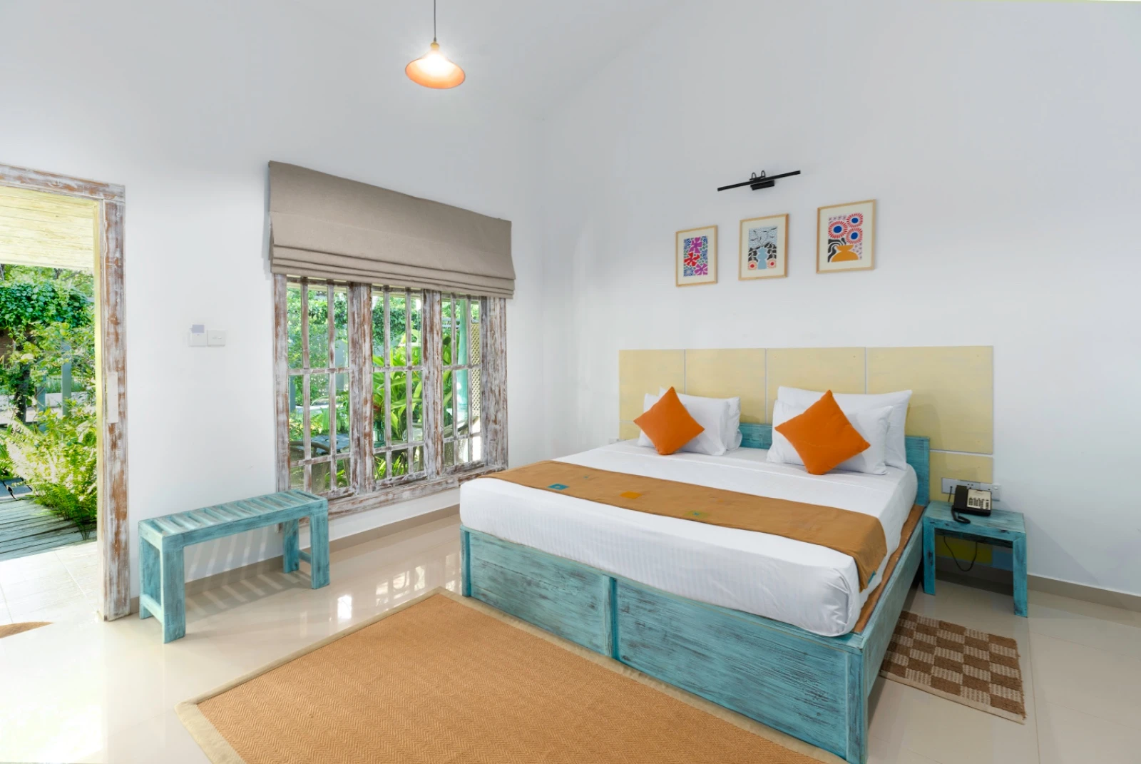 A bright guest room with a turquoise bed frame and a door onto the garden