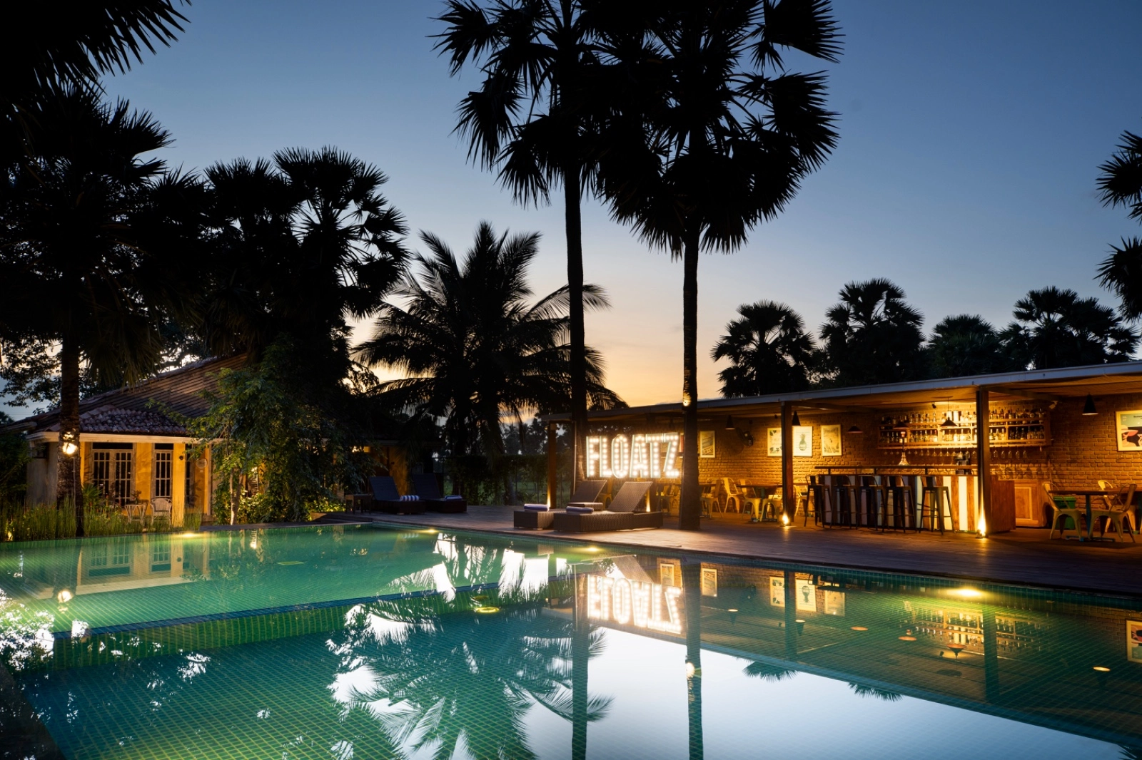 The pool at Palmera Eco Resort lit at dusk
