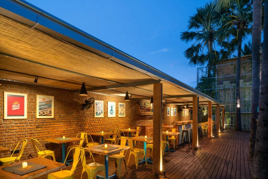 The covered bar terrace set with candlelit tables at dusk