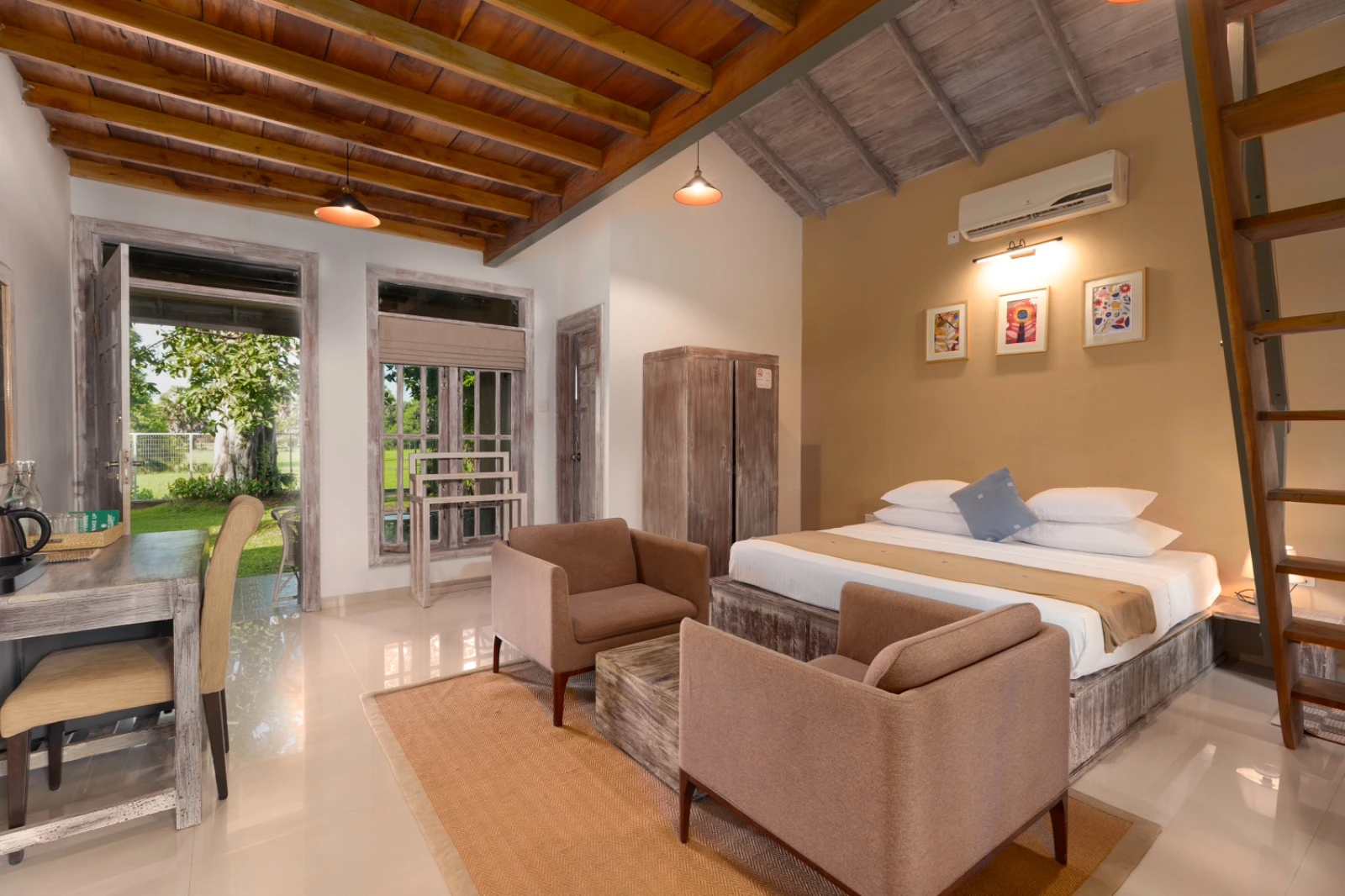 The king bed and armchairs in a Deluxe Family Chalet, under its timber roof