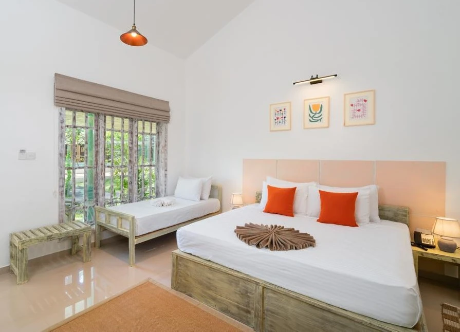 The king bed and single bed in a Deluxe Triple Room beside the window