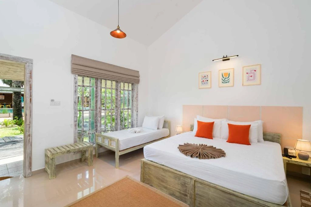 The king bed and single bed in a Deluxe Triple Room, with a door onto the garden