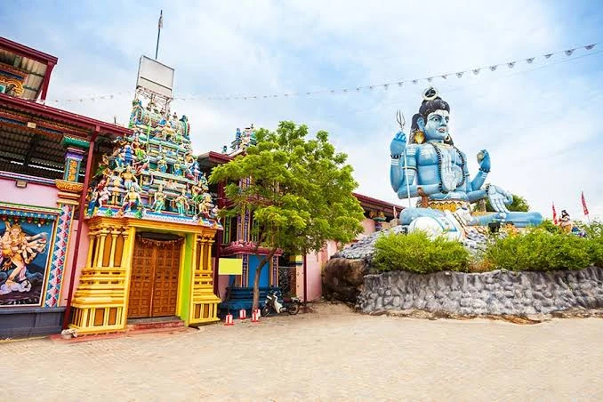 The painted gateway tower of Koneswaram Kovil beside a large statue of Lord Shiva