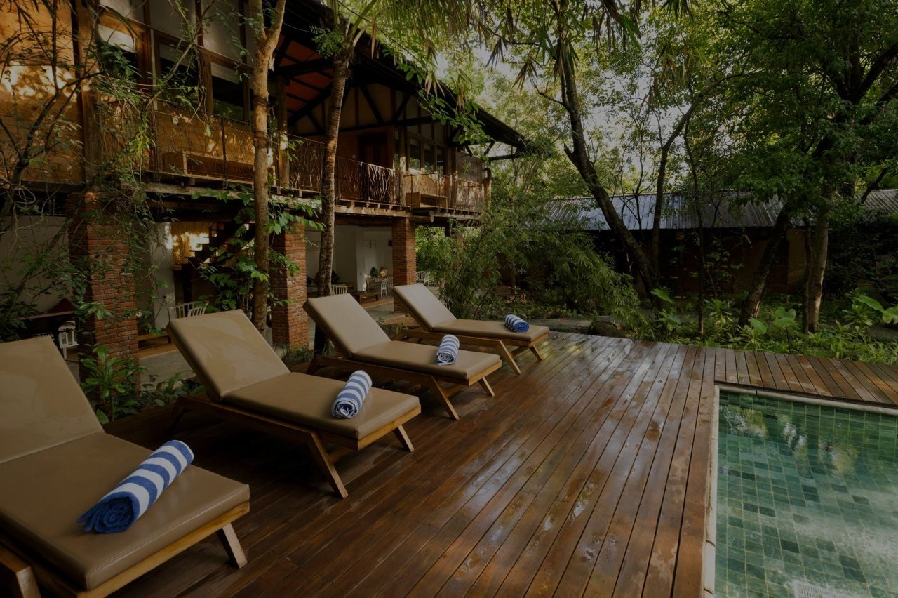 Sun loungers with rolled towels on the timber deck beside the pool at Varanya