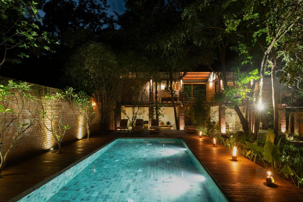 The pool at night, lamps along the deck and the guest wing lit behind