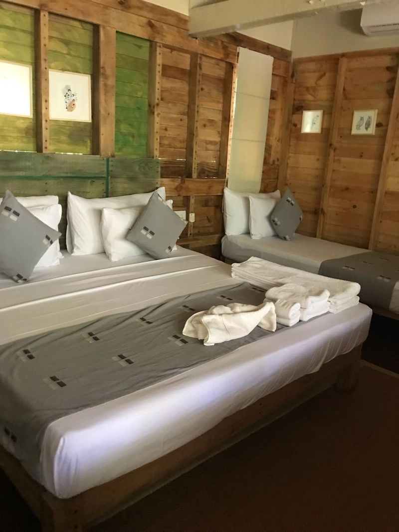 The beds in a Triple Room with Pool View against the timber wall