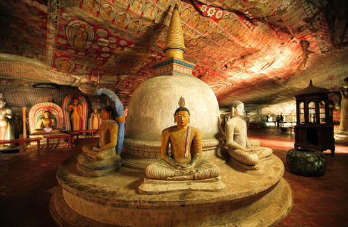 Seated Buddha statues around a stupa beneath the painted ceiling of the Dambulla cave temple
