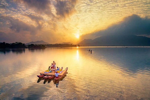 A raft on Habarana lake at sunset with hills beyond